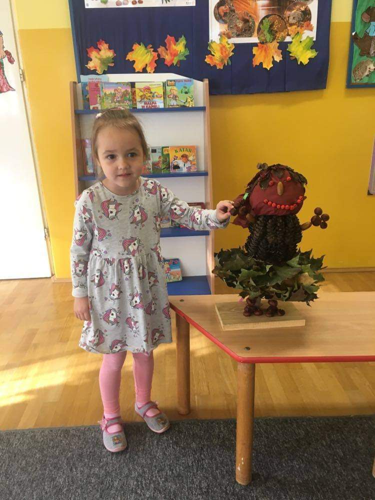 czterolatka prezentuje skrzata wykonanego z liści i innych darów jesieni