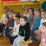 Dzieci siedzą na ławce i zainteresowaniem oglądają przedstawienie