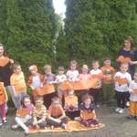 Dzieci trzymają pomarańczowe serca i pozują na tle plakatu  #dziengodnosci 